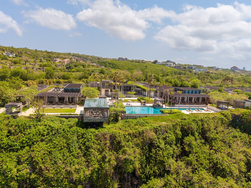 Aerial view of a luxurious villa with an infinity pool on a cliffside in Bali, Indonesia.