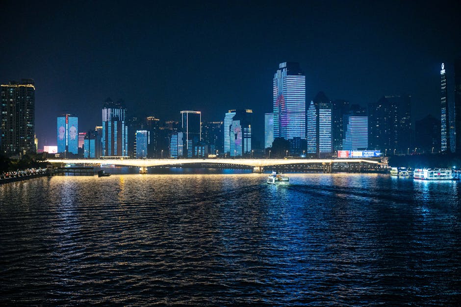 Stunning nighttime cityscape featuring illuminated skyscrapers and a reflective river view.
