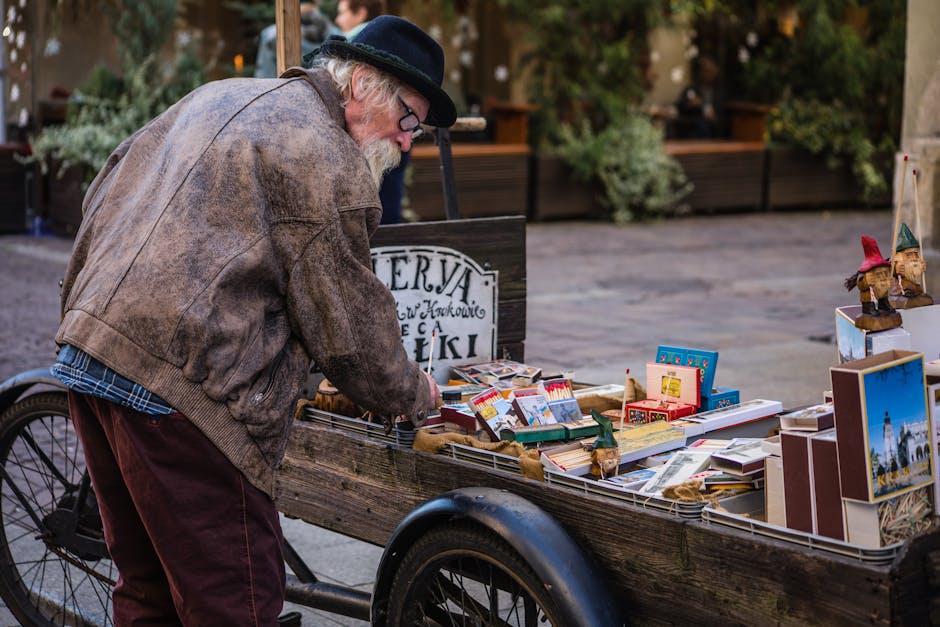 Elderly man browsing a wooden street stall filled with vintage items and postcards.