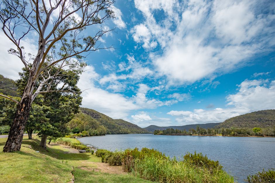 Beautiful landscape of a lake surrounded by mountains and a vibrant blue sky with scattered clouds.