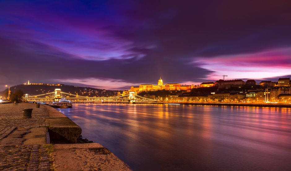 Scenic night view of Budapest's Chain Bridge and Danube River reflecting city lights.