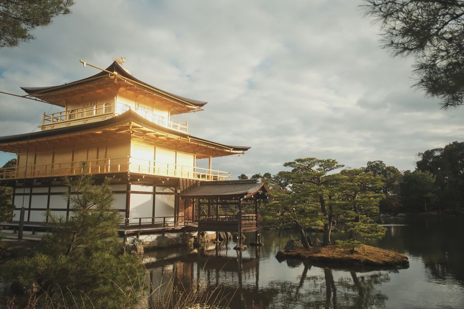 The Kinkaku-ji Temple in Kyoto, Japan, gleaming gold in sunlight and mirrored on still waters.