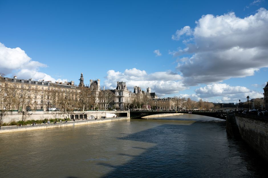 Elegant view of the Seine with historic Paris buildings under a blue sky.