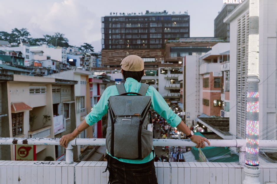 A person with a backpack gazes at a busy urban street from a high vantage point, capturing city life.