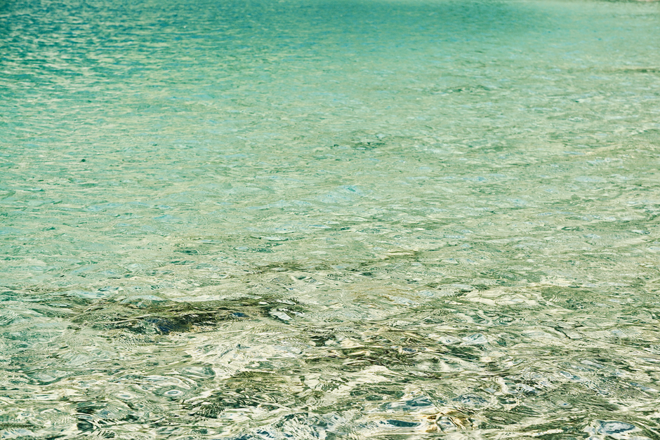 A serene image of tranquil, crystal clear turquoise water surface with gentle ripples.