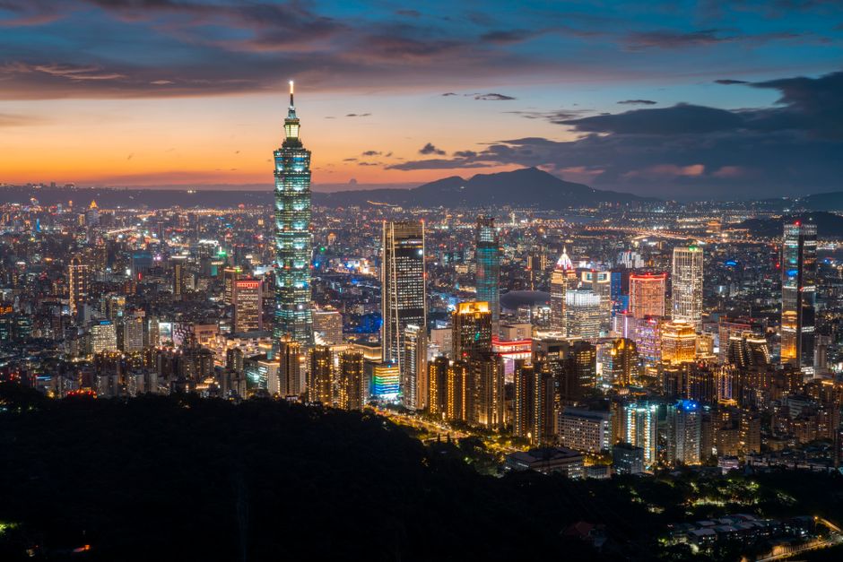A breathtaking aerial view of Taipei with the illuminated skyline featuring Taipei 101 at sunset.