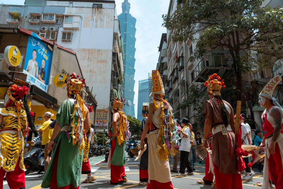 Traditional parade with costumes near Taipei 101 in urban Taiwan setting.