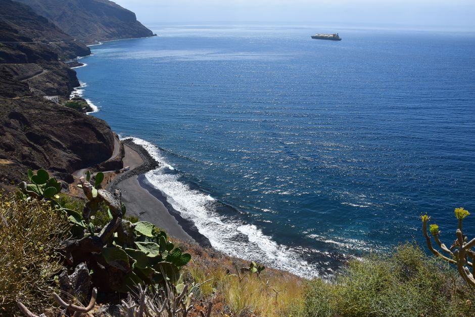 Breathtaking view of a rugged coastline with a distant cargo ship on a sunny summer day.
