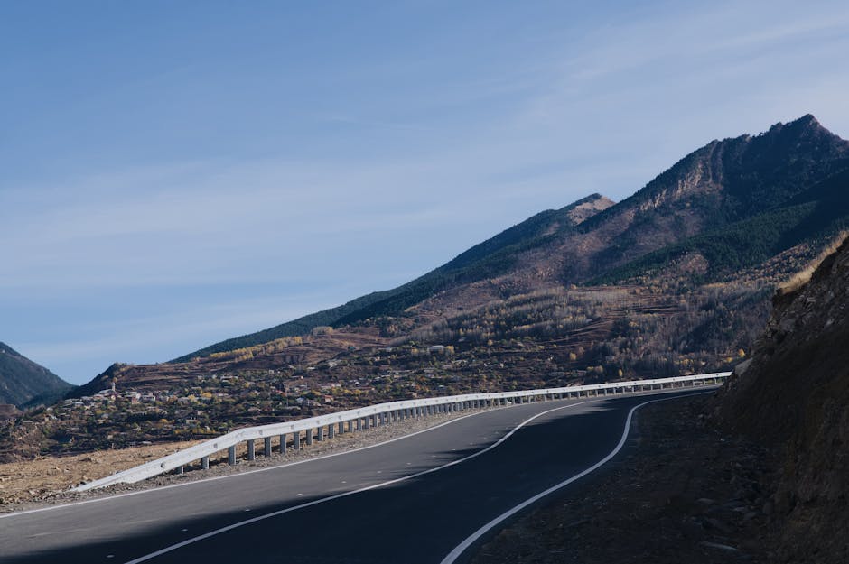 A winding road curves through a mountainous landscape with a rustic village nestled below.
