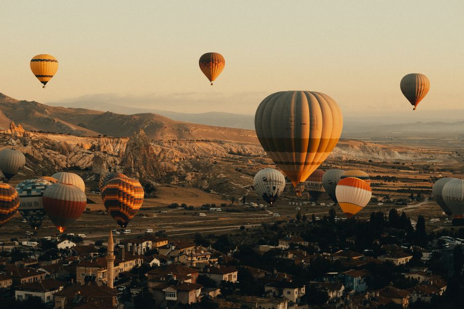 Colorful hot air balloons soaring over Cappadocia's unique landscape during sunset.