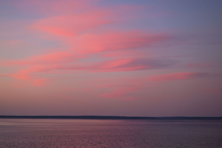 Beautiful pink clouds reflecting on a serene lake at sunset in Stamford, Connecticut.