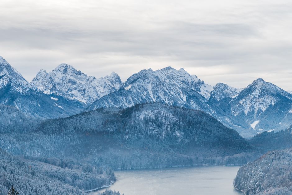 Breathtaking winter alpine landscape view with snow-covered Bavarian mountains and a serene lake.